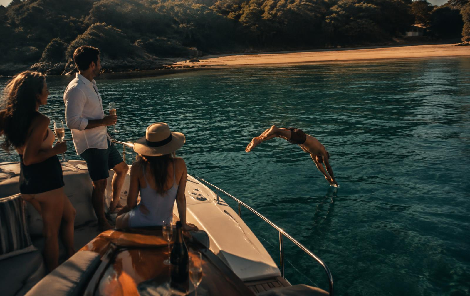 Friends swimming off a boat in a quiet harbour bay
